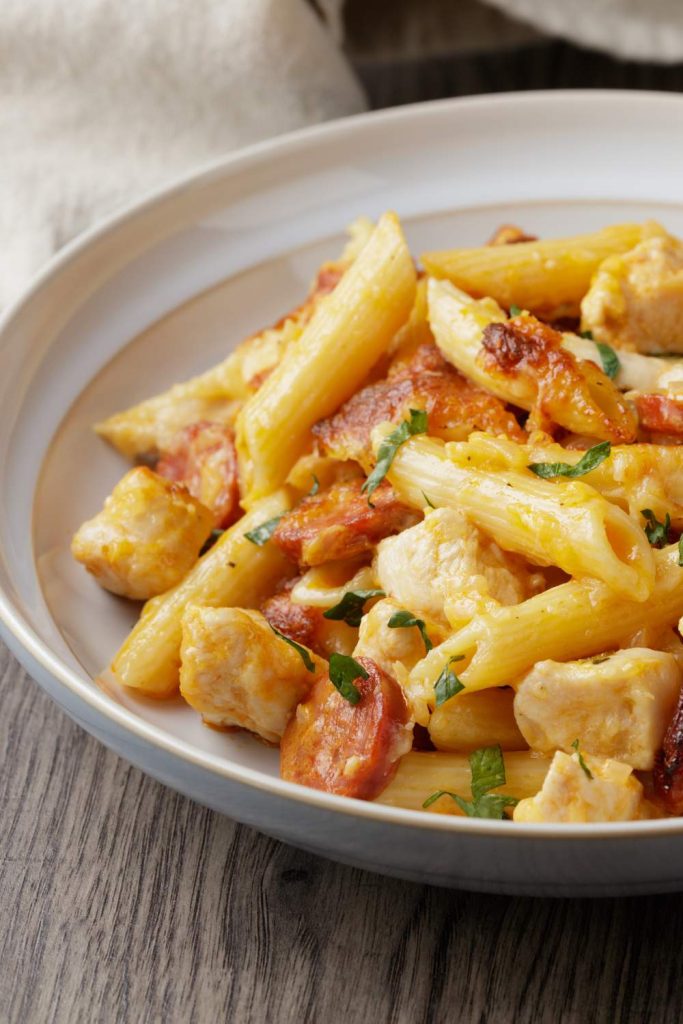 Fork lifting creamy chicken and chorizo pasta from a bowl.