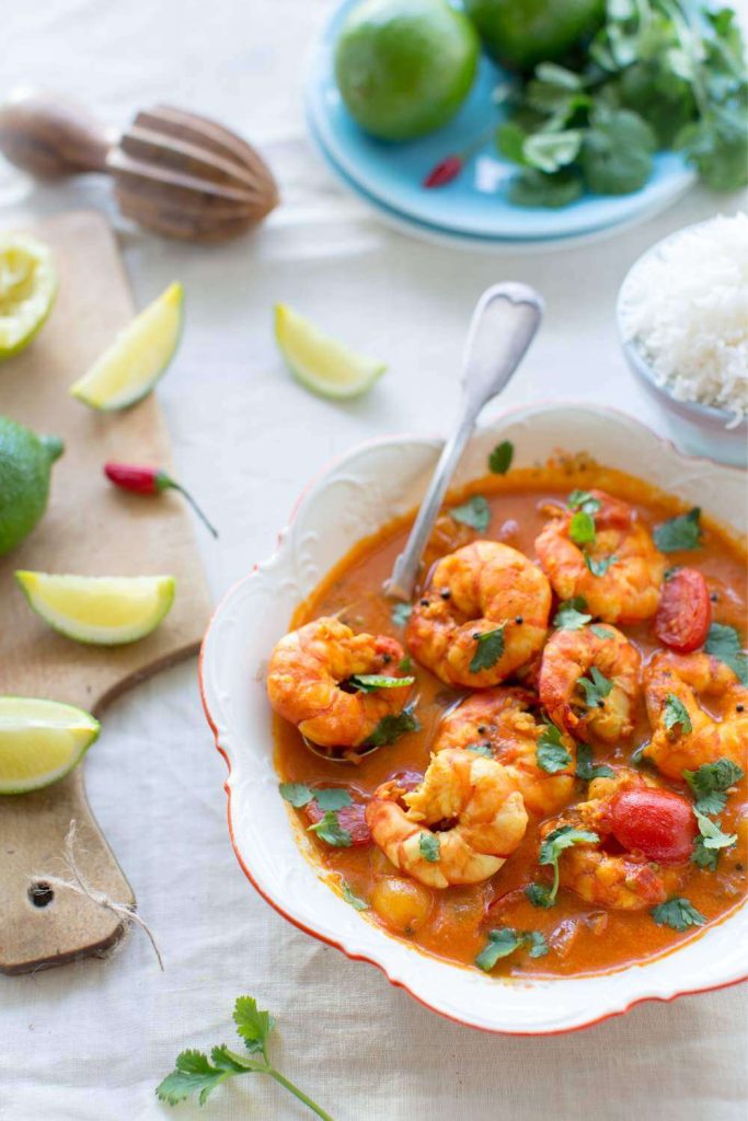 Bowl of prawn curry with leafy herbs.