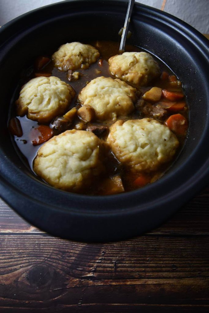 Overhead view of Aunt Bessie dumplings in a slow cooker, surrounded by a savory stew.