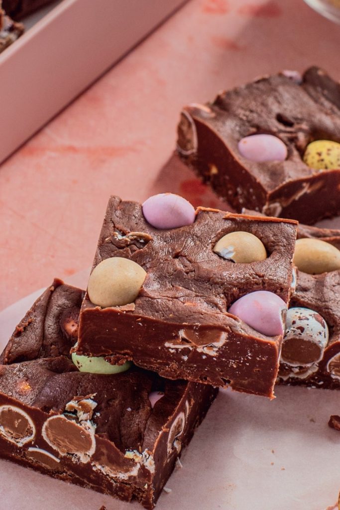 Mini Egg Fudge with colorful mini eggs on a pink surface.