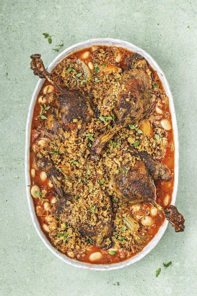 Slow cooker duck legs cassoulet in an oval dish.