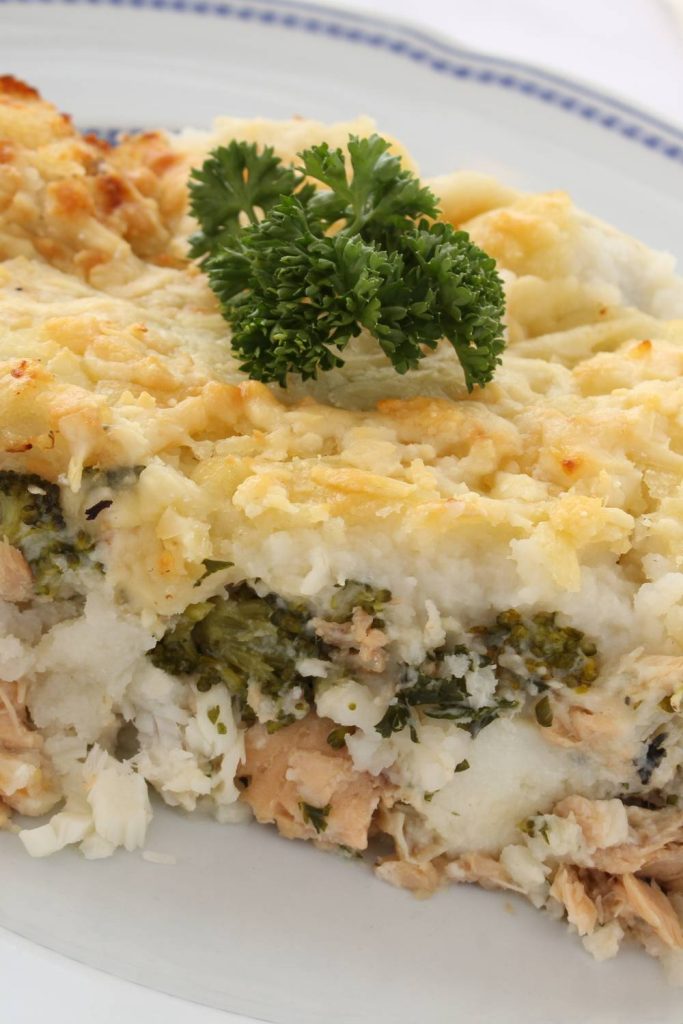 Layered slow cooker fish pie with parsley garnish on top.