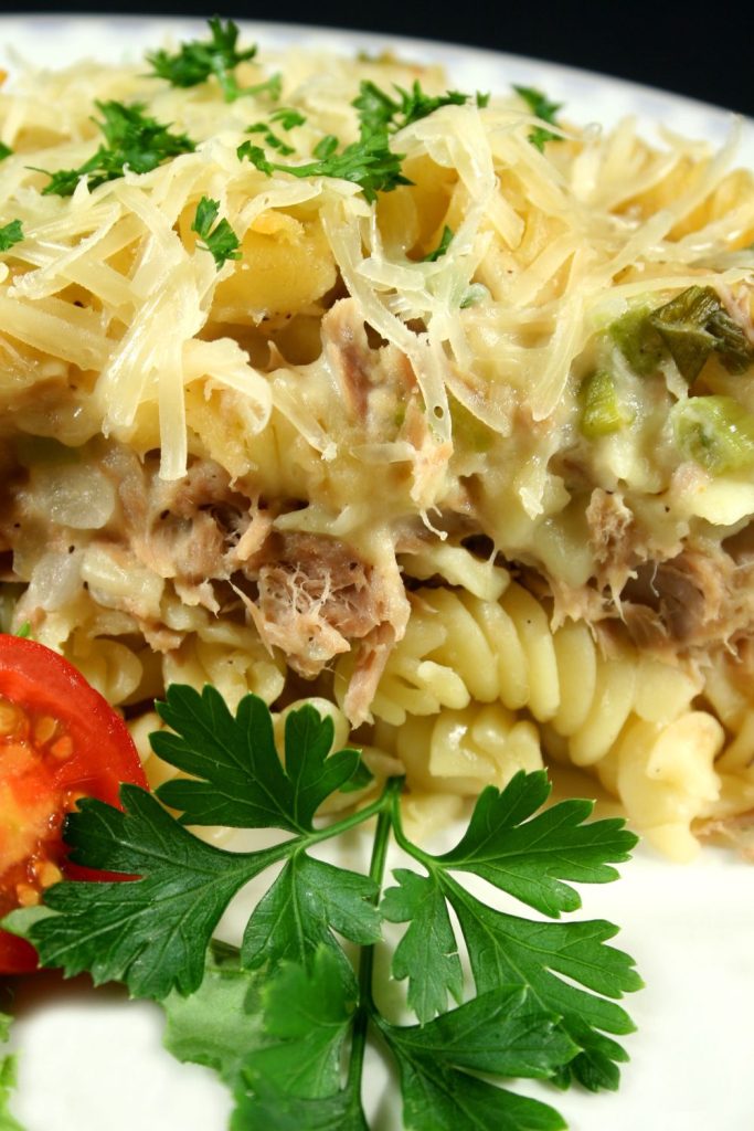 Close-up of a creamy tuna pasta bake topped with melted cheese and parsley.