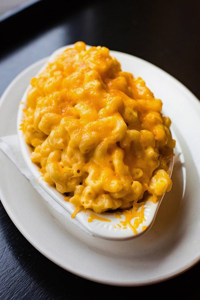Bowl of macaroni covered in melted cheddar cheese.