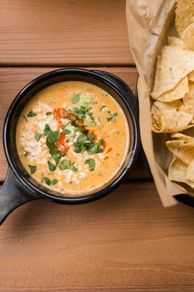 Queso dip in a pot with chips on the side.