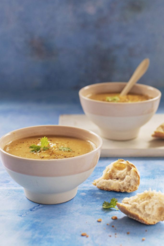 Creamy spiced parsnip soup in a ceramic bowl garnished with fresh herbs.