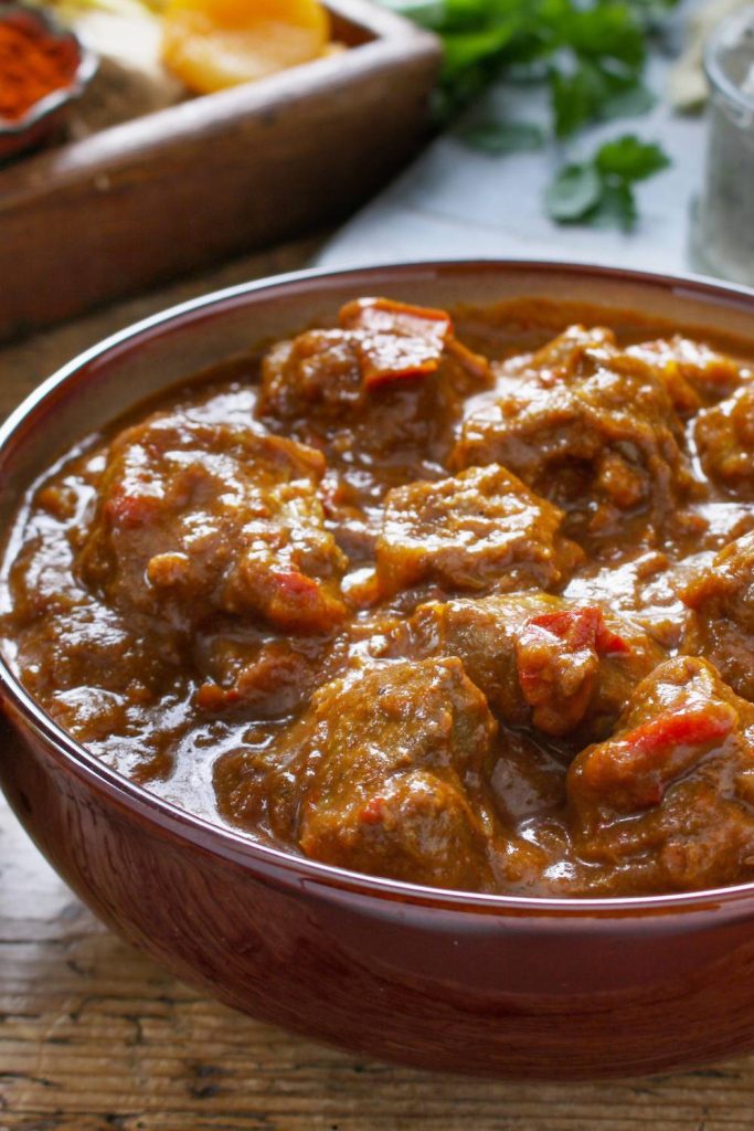 Brown bowl of beef curry with sauce.