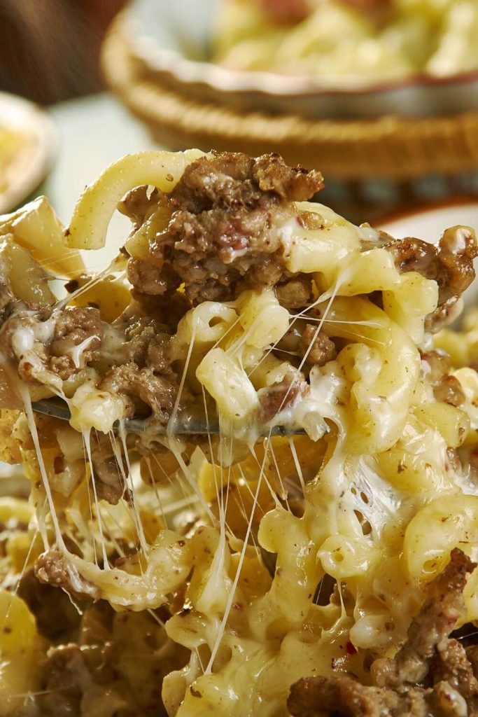 Close-up of slow cooker cheeseburger pasta in a dish showing melted cheese and seasoned beef.