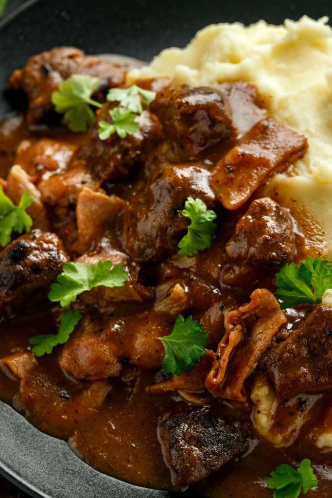 A plate of liver and bacon casserole with smooth mashed potatoes, ready to be enjoyed.
