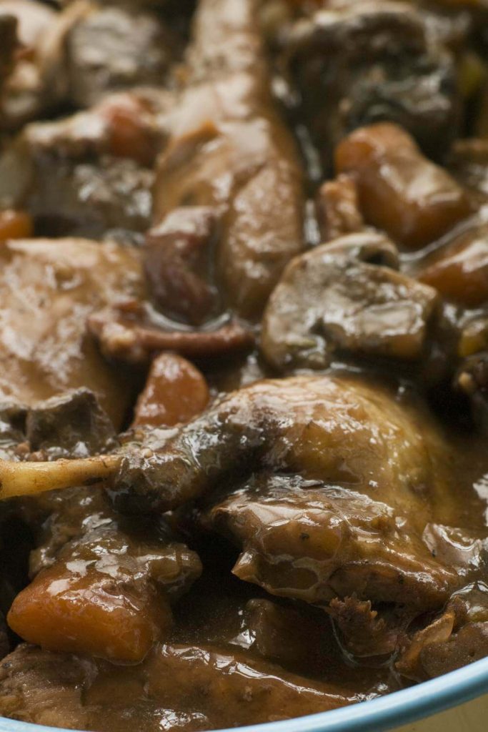 Close-up of tender pheasant meat in a rich red wine gravy, prepared in a slow cooker.