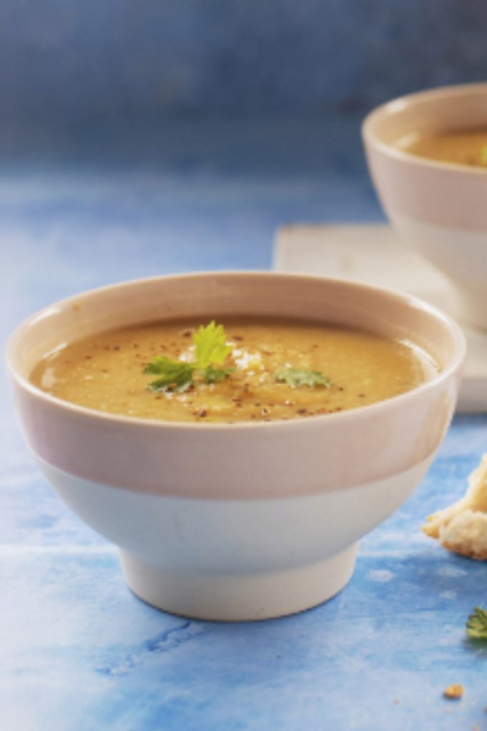 Slow cooker parsnip soup served with a spoon and crusty bread on the side.