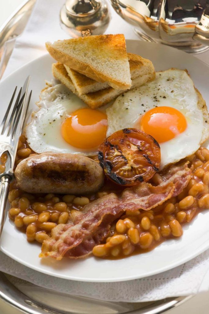  A full English breakfast served elegantly with eggs, bacon, beans, sausages, and grilled tomato.