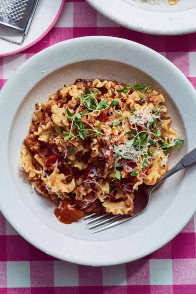 a bowl of sausage ragu with pasta and cheese, ready to enjoy.