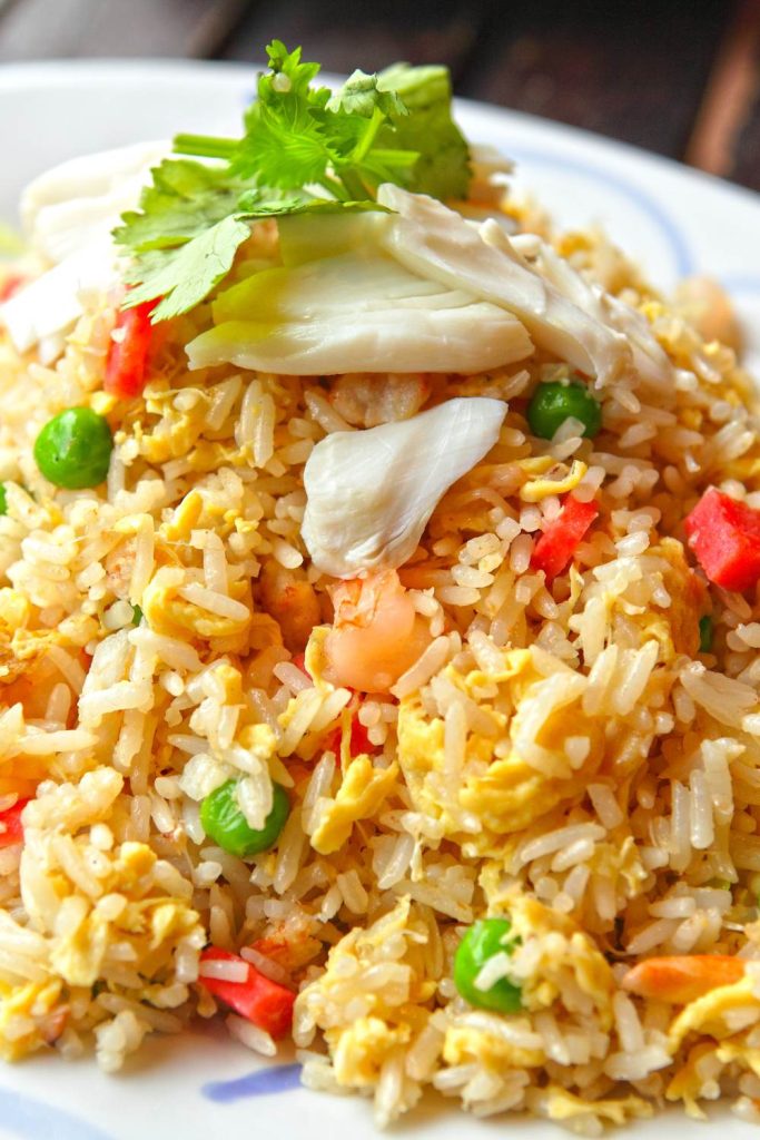 Plate of chicken fried rice with vegetables topped with fresh herbs.