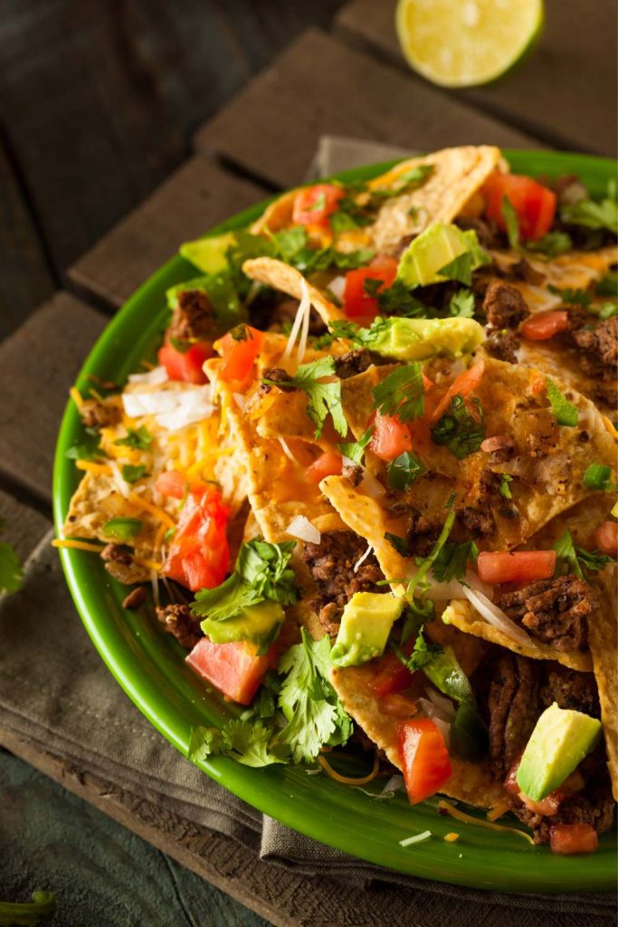 Slow Cooker Beef Nachos with melted cheese and avocado.