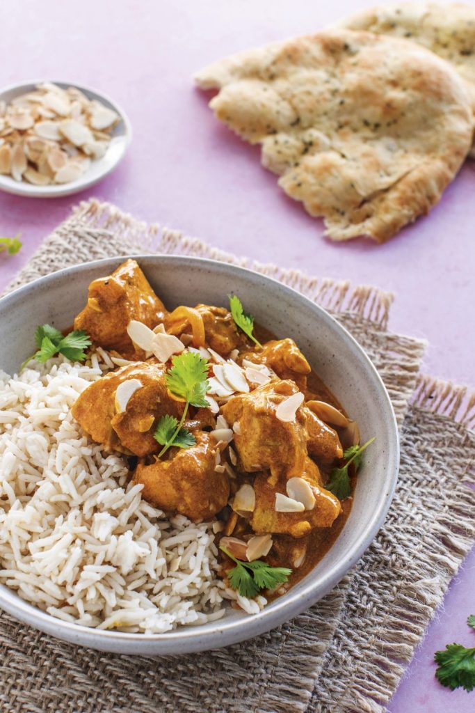 Slow Cooker Healthy Chicken Korma served with white rice and garnished with almonds and fresh herbs.