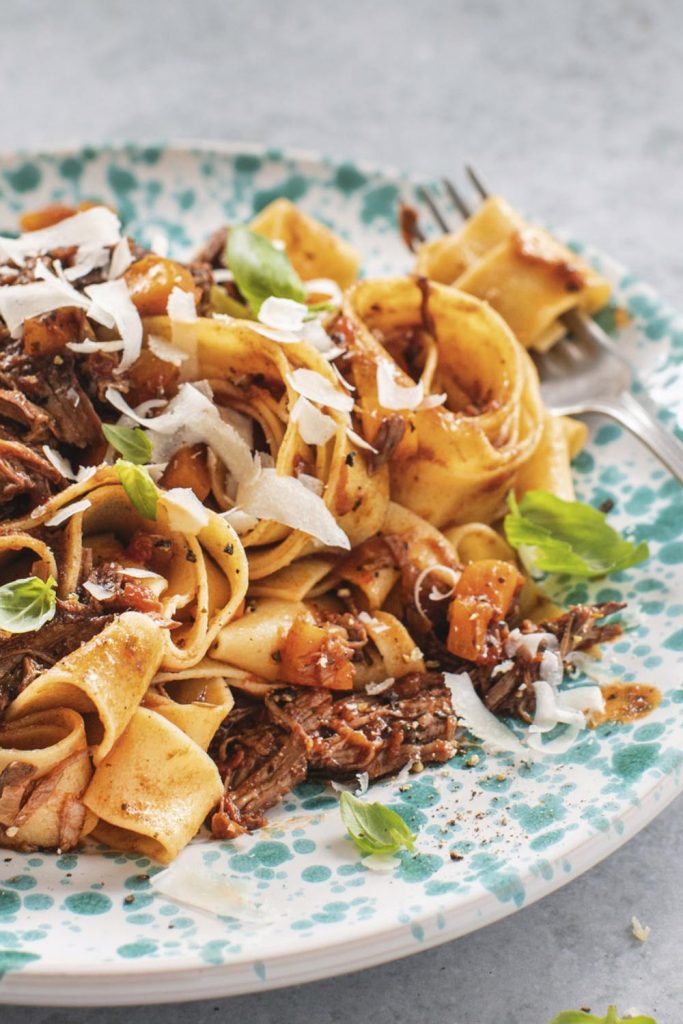 pappardelle pasta mixed with Slow Cooker Porterhouse Ragu, topped with cheese and basil.