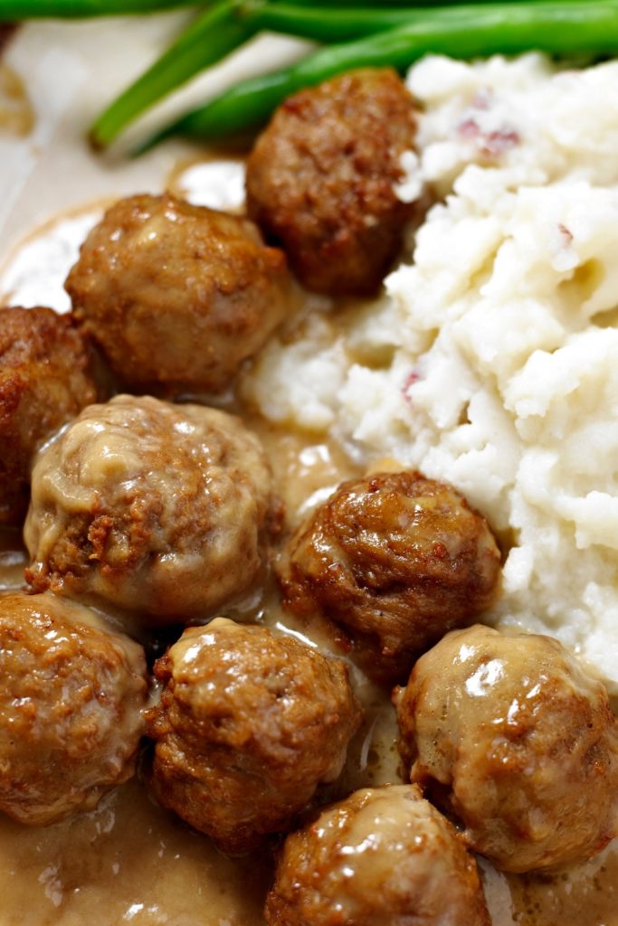 Slow Cooker Meatballs in gravy over mashed potatoes.