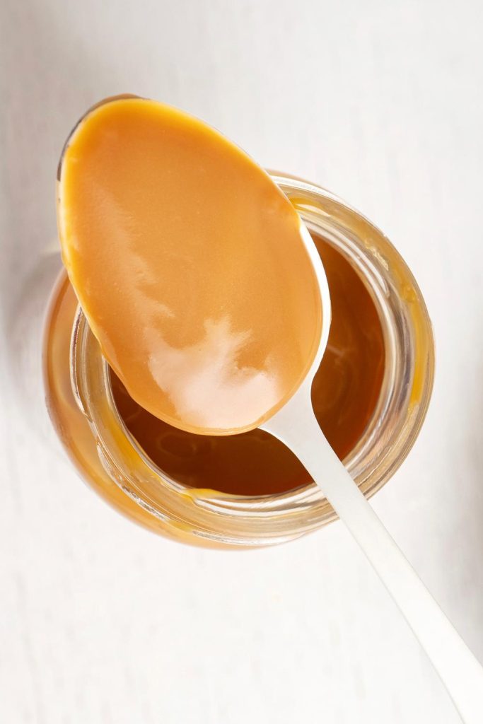 Homemade caramel in a jar with a spoon, made from condensed milk.