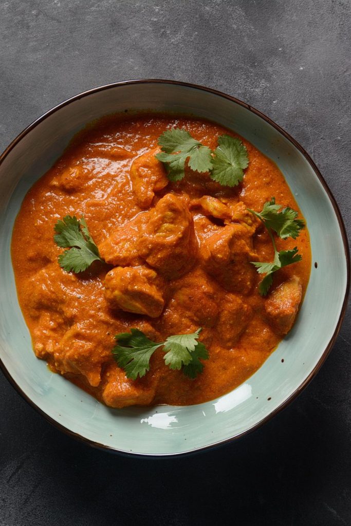 Slow Cooker Tandoori Chicken in a blue bowl with cilantro on top.