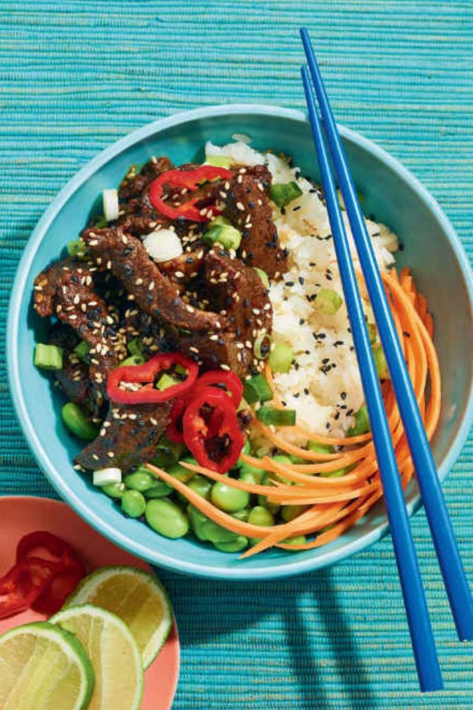 A bowl of teriyaki beef with rice and vegetables, chopsticks on the side.