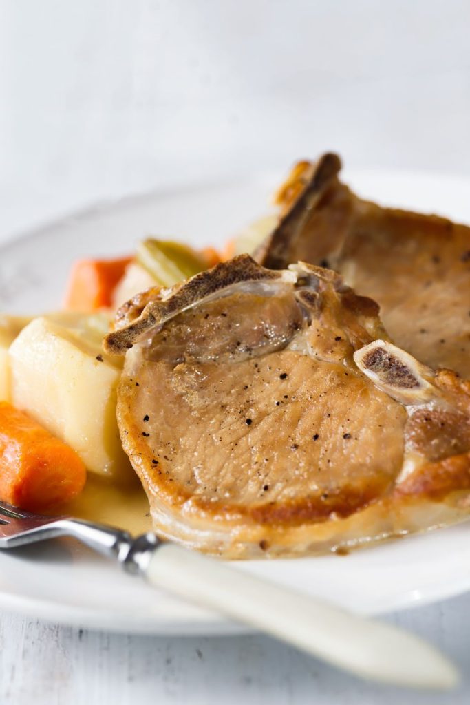 juicy pork chops with vegetables on a plate, emphasizing the flavorful gravy.