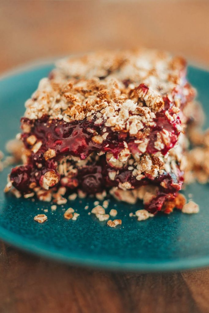 Blue plate with slow cooker berry crumble and crumbs around.