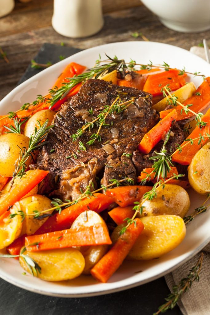 Plate with slow cooked Ribeye steak, carrots, and potatoes on a table.
