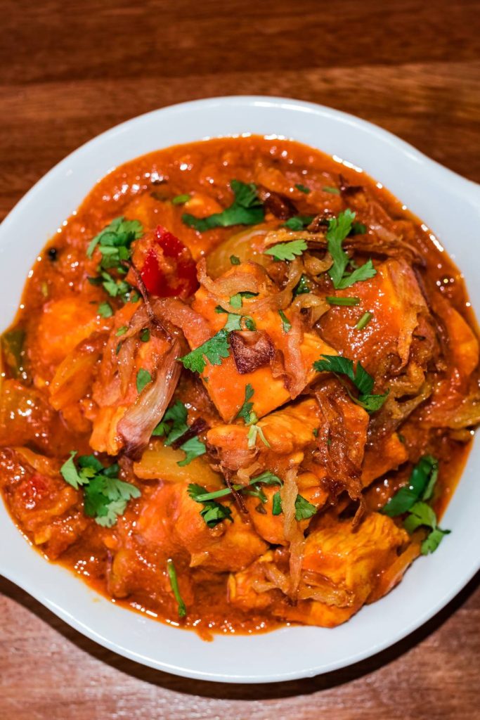 A bowl of slow cooker chicken bhuna with herbs on top.