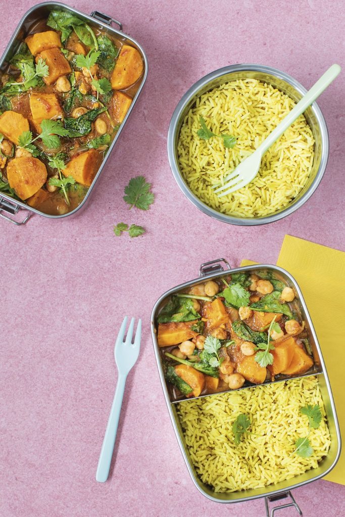 Overhead shot of Slow Cooker Sweet Potato Curry with vibrant yellow rice in separate containers.