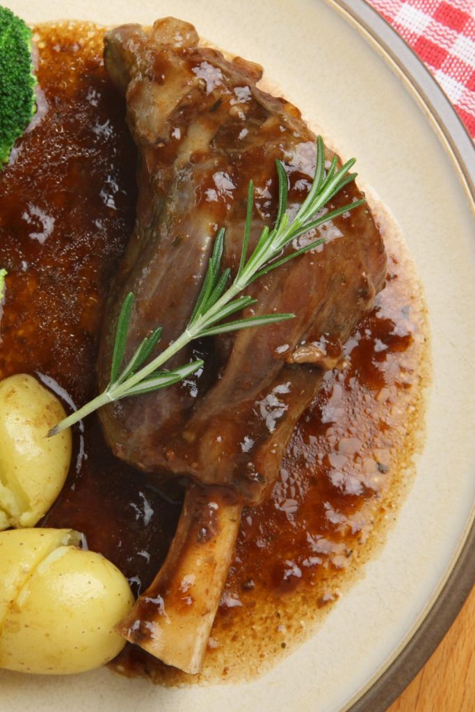 Top view of a Slow Cooker Lamb Shank with gravy and rosemary.