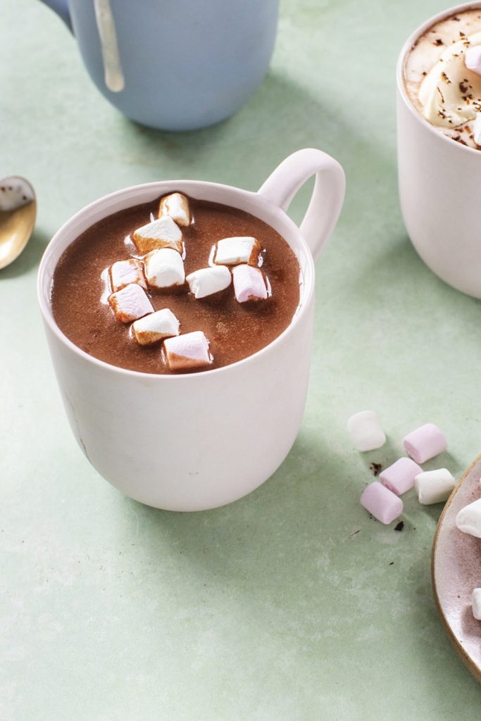 a creamy hot chocolate in a white mug, topped with marshmallows.