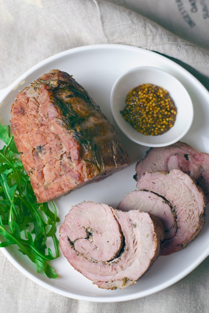 Slices of 3 Ingredient Pork Roast served on a plate with greens, showcasing the juicy and tender meat.
