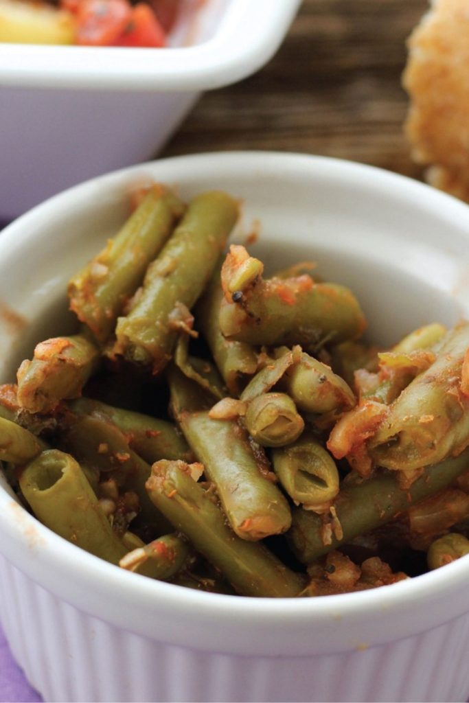 Greek green beans in tomato sauce in a white bowl.