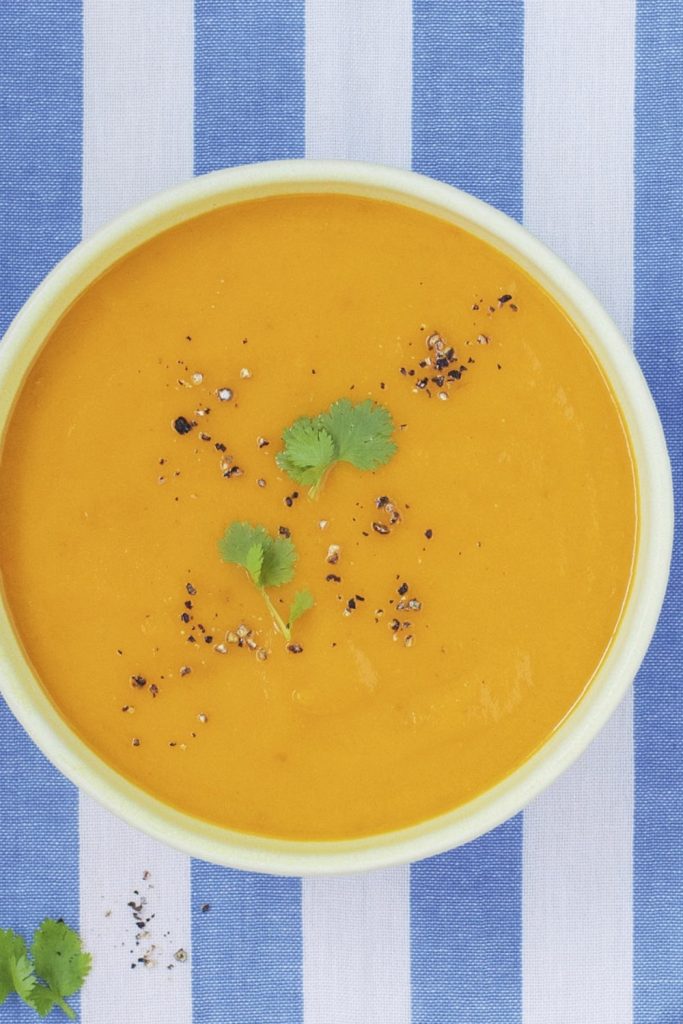 carrot and coriander soup garnished with herbs and spices.