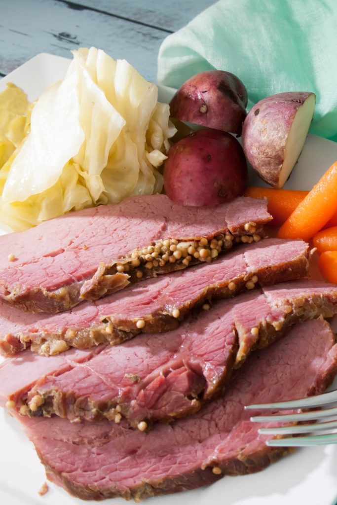 Slow Cooker Silverside in Foil served with potatoes, carrots, and cabbage on a plate.