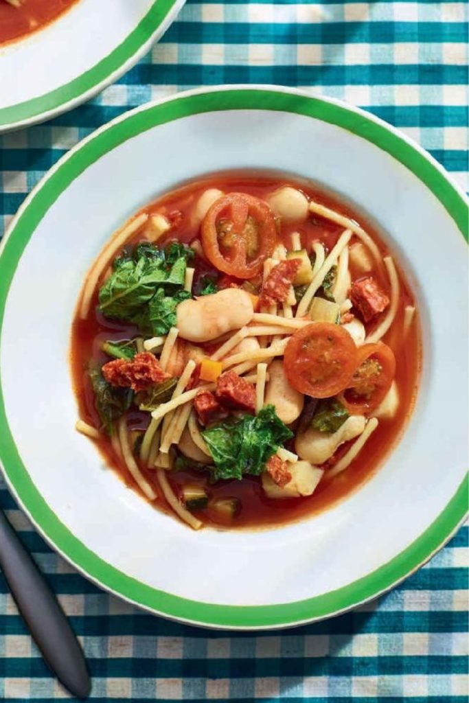 Slow Cooker Smoky Minestrone Soup with tomatoes, beans, and greens in a green-rimmed bowl.
