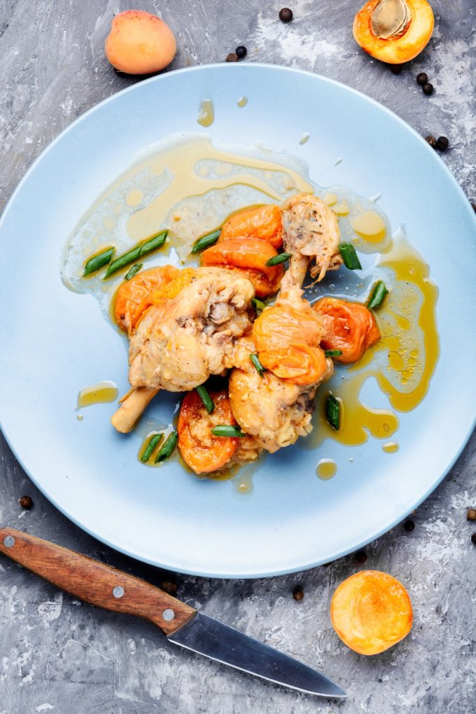  Slow Cooker Apricot Chicken with apricots and green onions on a blue plate.