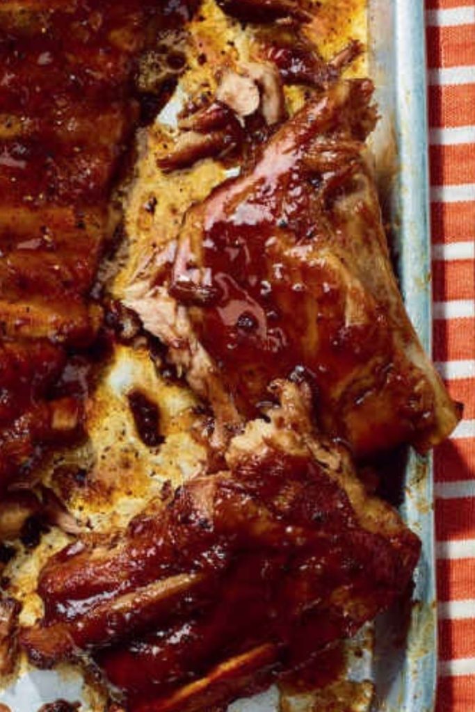 Slow Cooker BBQ Ribs on a baking sheet, covered in BBQ sauce.