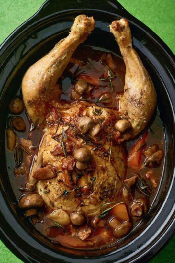 Slow Cooker Coq Au Vin Chicken with mushrooms and herbs in a black slow cooker.