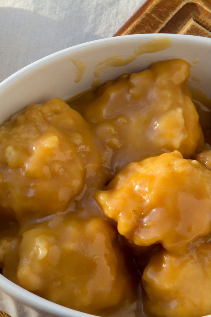 Slow Cooker Golden Syrup Dumplings in a white dish, covered in golden syrup.