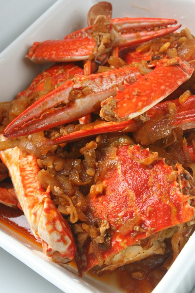 Slow Cooker Sweet Chilli Mud Crab in a white dish with onions and sauce.