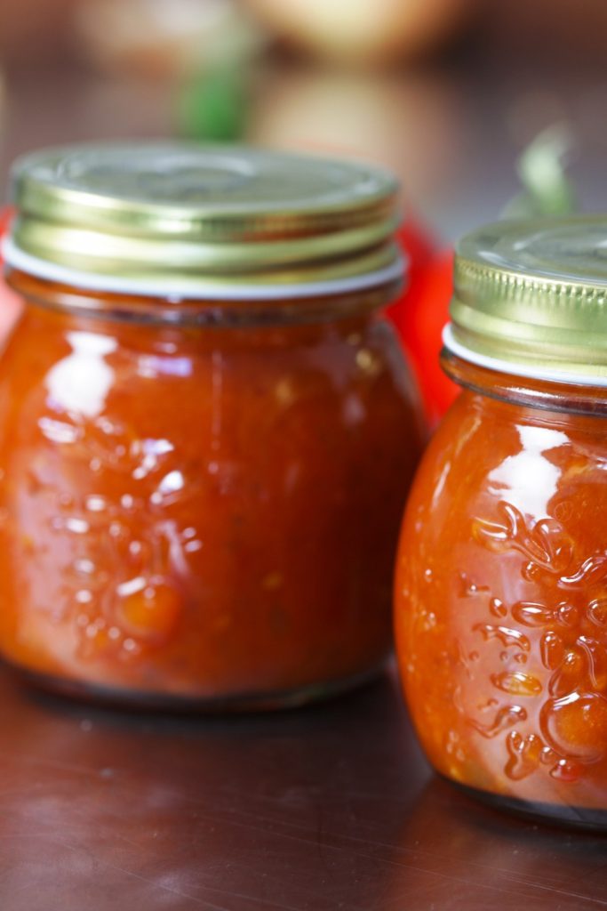 two jars of Slow Cooker Tomato Relish on a table.
