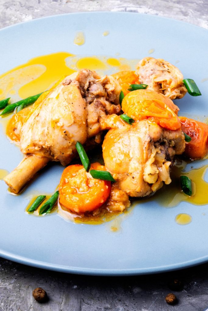Slow Cooker Apricot Chicken with carrots and green onions on a blue plate.