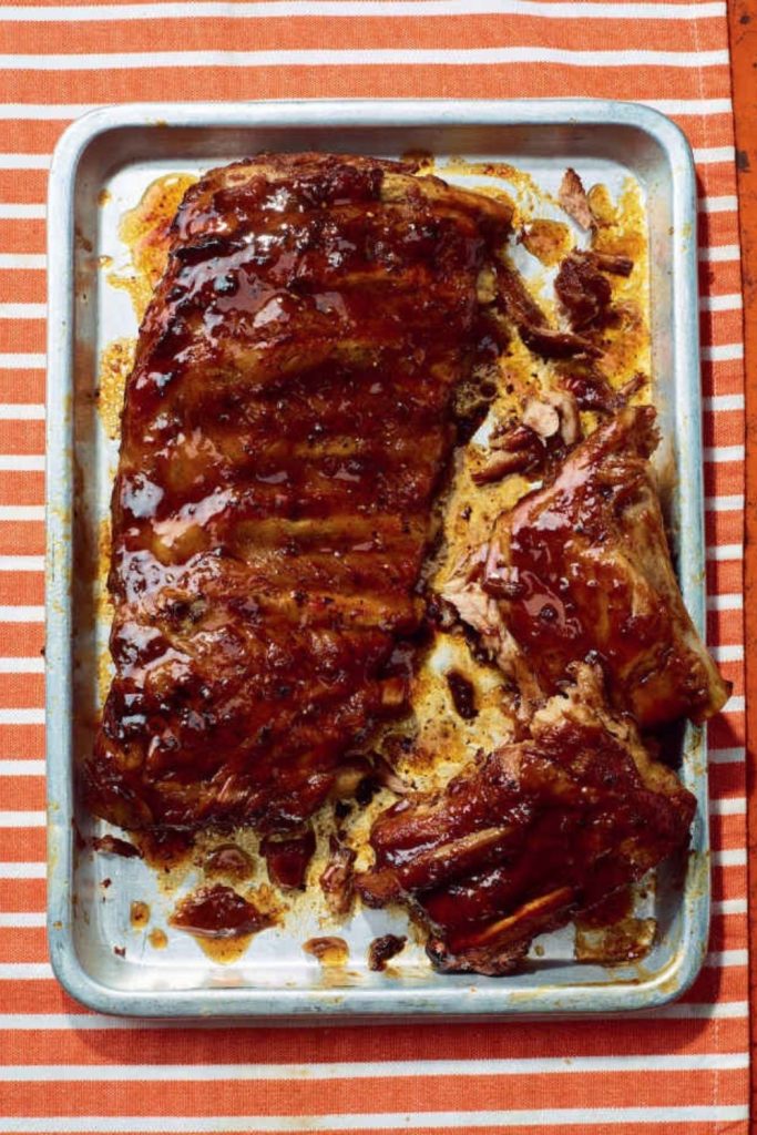 Slow Cooker BBQ Ribs on a baking sheet, covered in sauce.