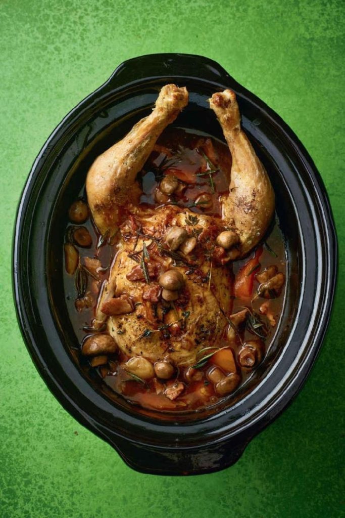 Slow Cooker Coq Au Vin Chicken with mushrooms and herbs in a black slow cooker.