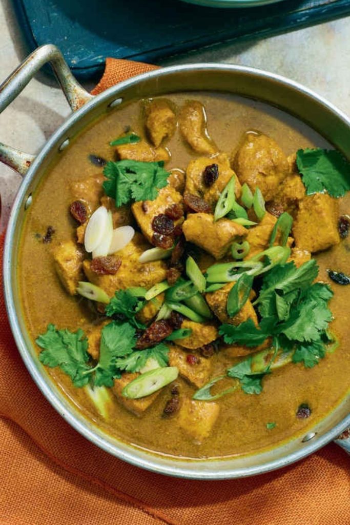 Aromatic Slow Cooker Coronation Chicken Curry garnished with almonds and green onions.