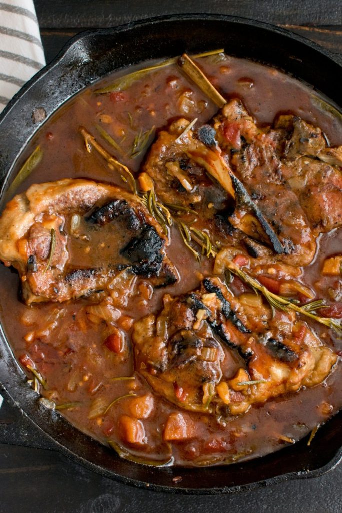 Slow Cooker Lamb Obsession with rosemary and tomatoes in a skillet.