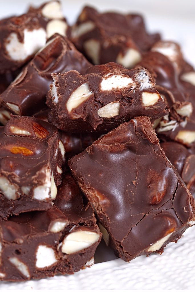 Slow Cooker Marshmallow Fudge with chocolate chunks and nuts on a plate.