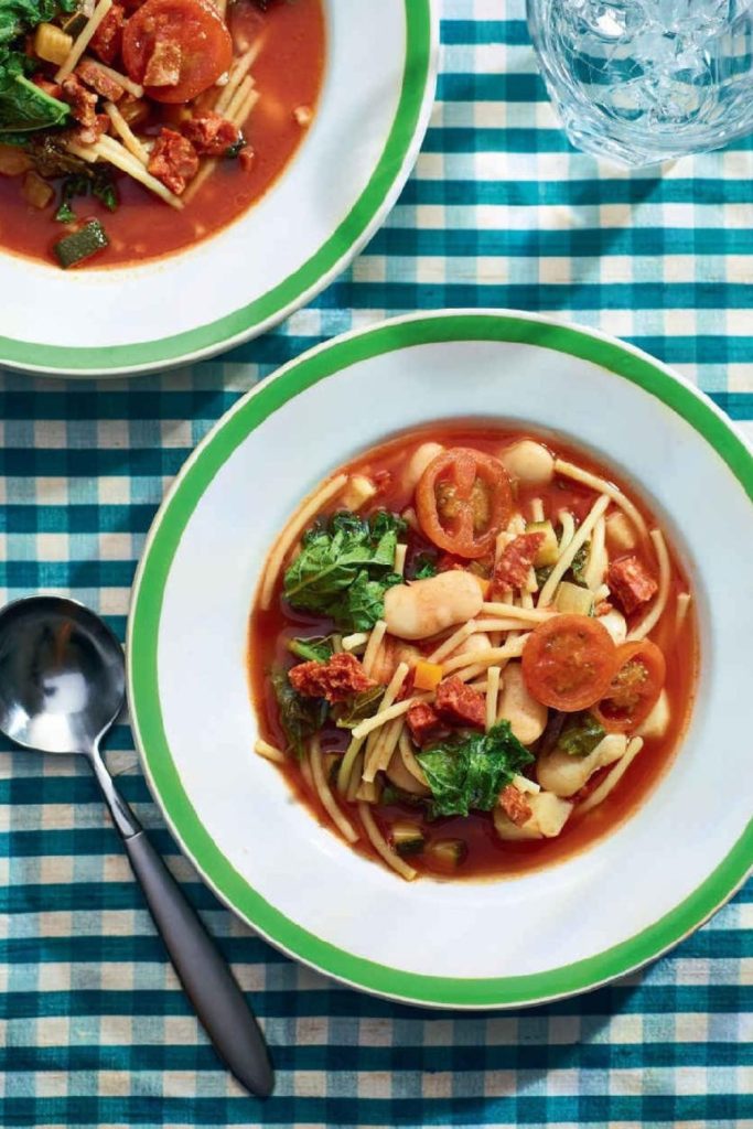Slow Cooker Smoky Minestrone Soup with tomatoes, beans, and greens in a green-rimmed bowl.